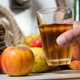 glass of apple cider held beside apples